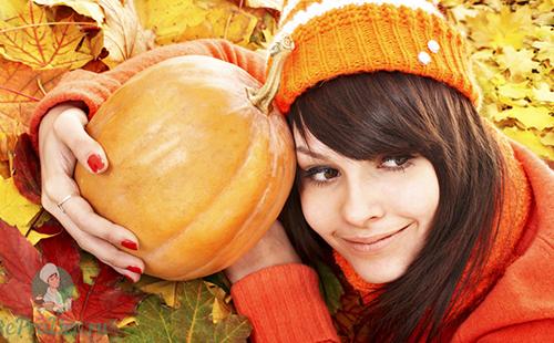 Момиче в оранжева шапка прегръща плодовете на есента