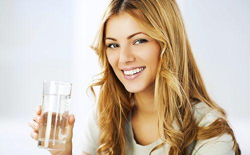 Усмихнато момиче, което държи чаша вода