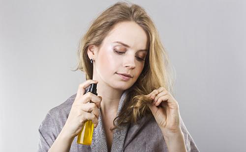 Момиче с бутилка масло изследва краищата на косата