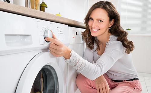 Жена с усмивка се включва на пералнята