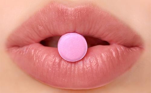 Розова таблетка върху устните