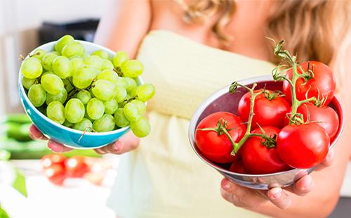 Жената държи домати и грозде в чаши