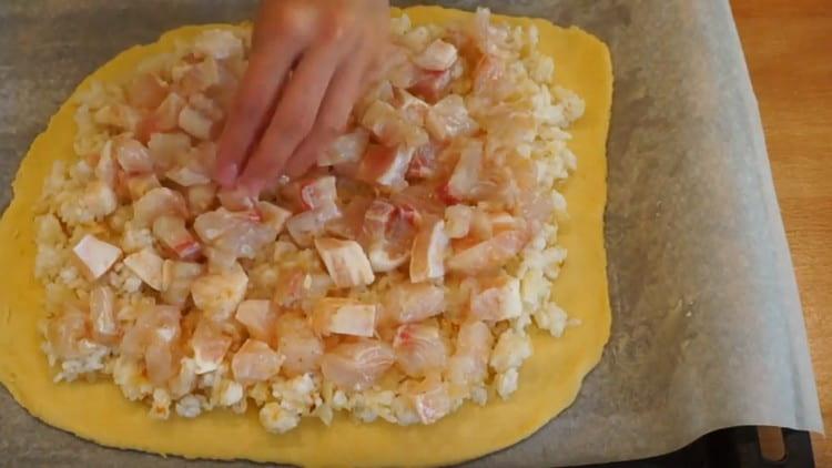 Разстиламе слой тесто върху лист за печене, върху него изравняваме ориза с лук, а отгоре разпределяме рибата.
