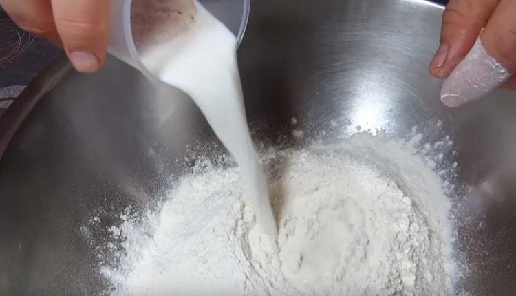 В пресятото брашно въвеждаме мляко с мая.