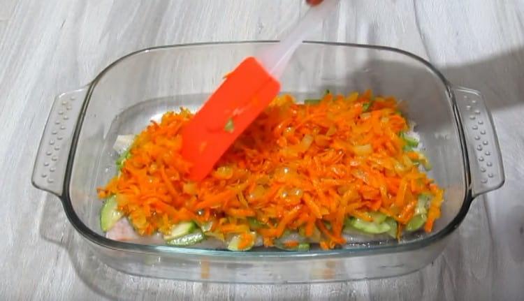 Отгоре на рибеното филе разпределяме слоя от тиквички, а върху него вече моркови с лук.