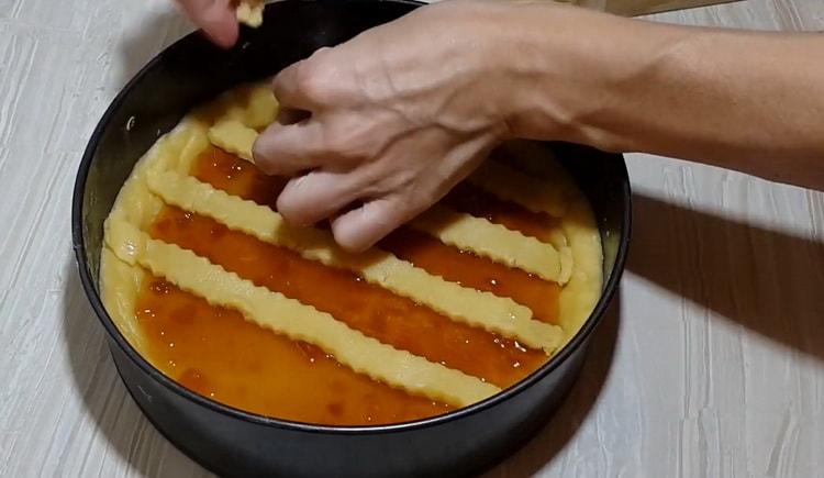 За да приготвите торта с къси хлебчета със сладко, поставете ивици тесто върху пълнежа