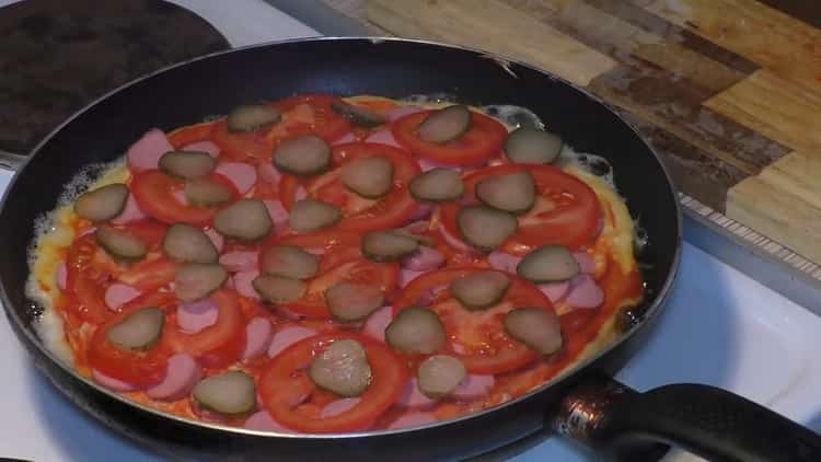 За да направите пица в тиган, сложете краставици върху соса