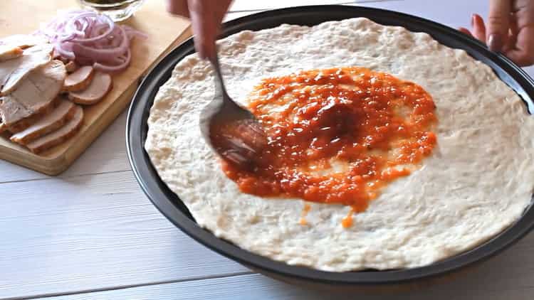 За да направите пица с пиле, намажете формата със сос