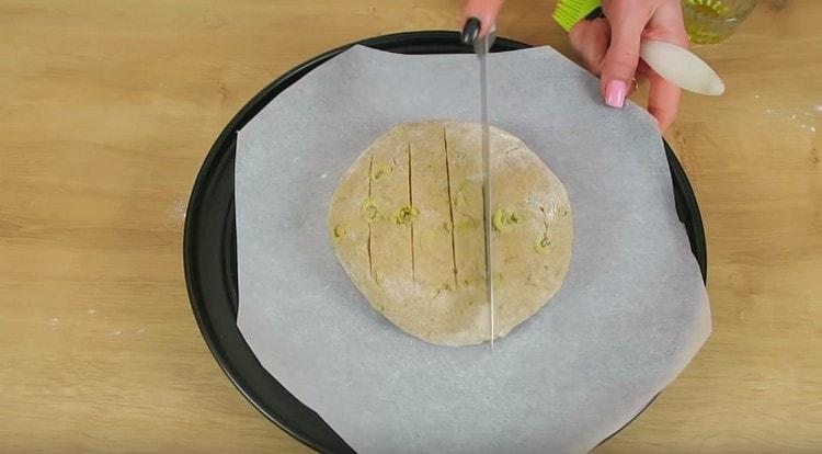 След като оформите кръгъл хляб, го сложете върху лист за печене, покрит с пергамент, и направете плитки разрези на хляба с нож.