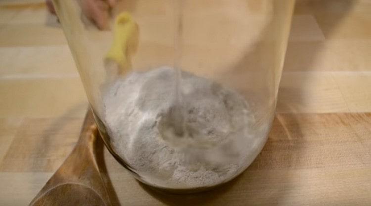 Поставете ръжено брашно в буркан и добавете към него топла вода.