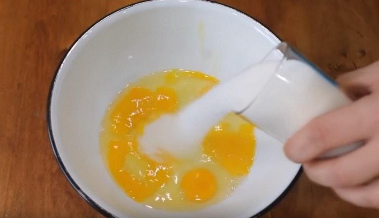 Добавете захарта към яйцата.