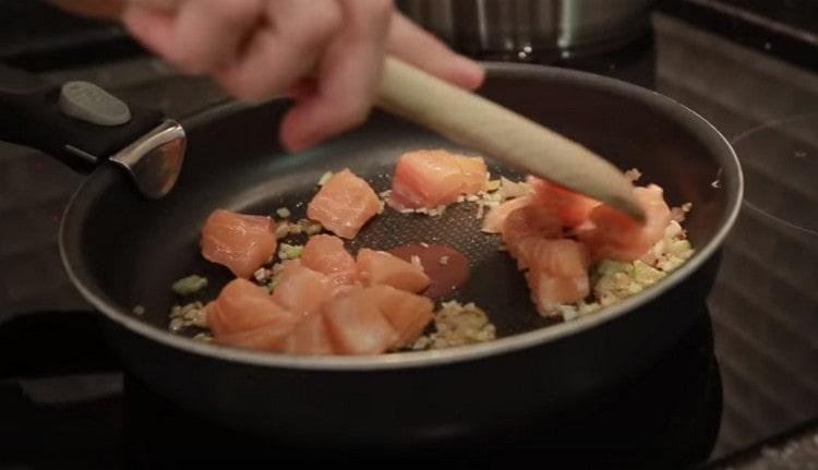 Společně s nasekaným česnekem rozprostřete losos na pánvi na cibuli.
