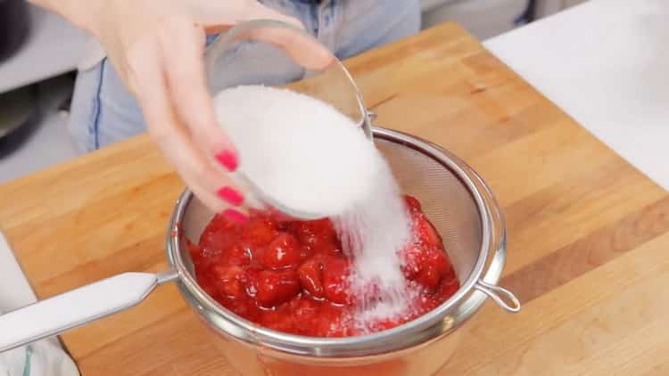 За да направите ягодов чийзкейк, смесете плодовете със захарта.