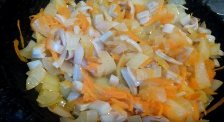 Запържете лука с морковите и резените калмари в тиган.