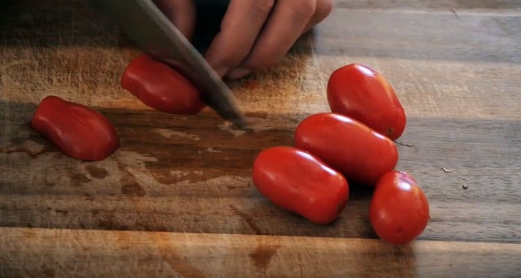 Нарежете чери доматите на четвъртинки.